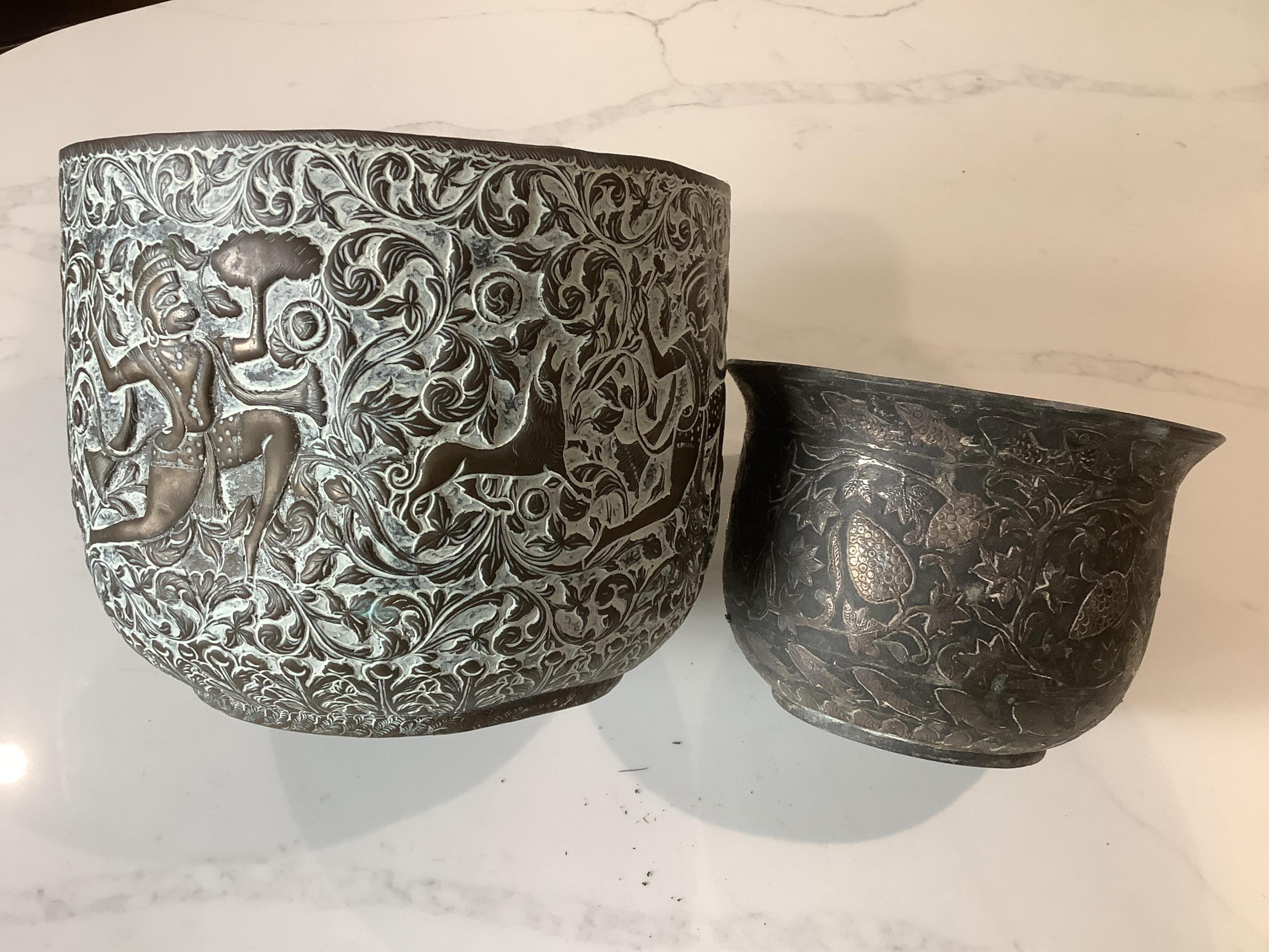 An Indian bidriware jardiniere decorated with fruiting plants and fish, 12.5cm and an embossed brass jardiniere decorated with monkey gods, 17.5cm.